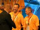 Mindis Jukna, LY4L (left), and Gedas Lucinskas, LY9A (in yellow tops), of Lithuania, are congratulated by WRTC 2018 Chairman Chris Jannsen, DL1MGB, at the closing ceremony.